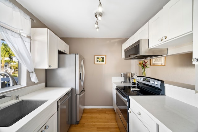 kitchen with white cabinetry, sink, stainless steel appliances, and light wood-type flooring