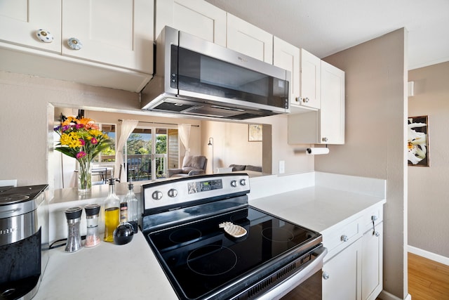 kitchen with hardwood / wood-style flooring, stainless steel appliances, and white cabinets