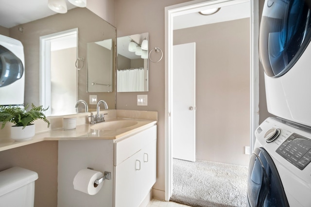 bathroom featuring stacked washing maching and dryer, vanity, and toilet