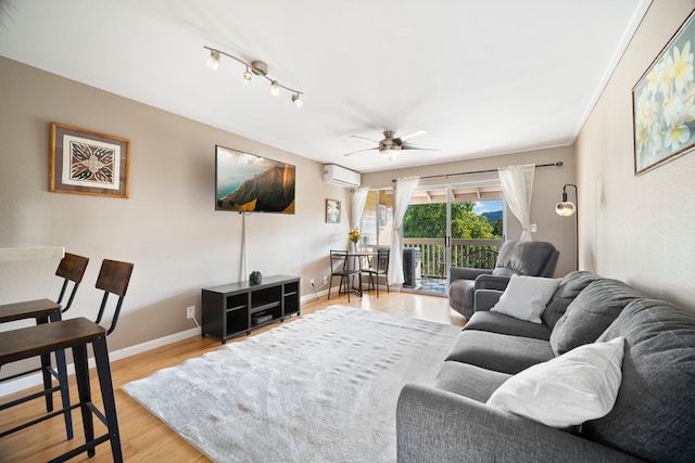 living room with an AC wall unit, ceiling fan, and light hardwood / wood-style flooring