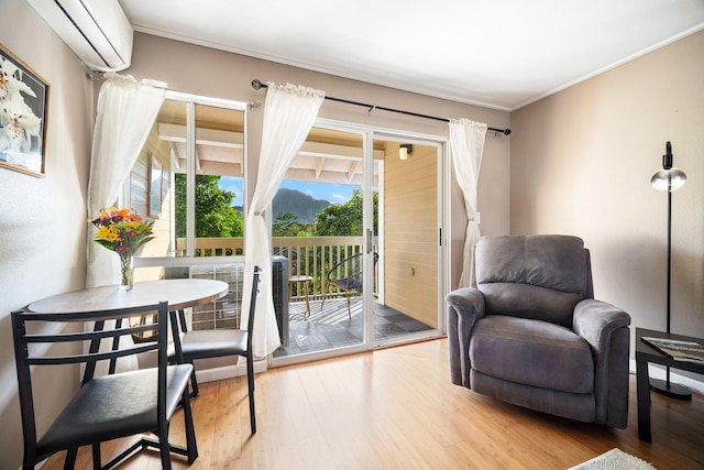 sitting room featuring hardwood / wood-style flooring, ornamental molding, and a wall unit AC