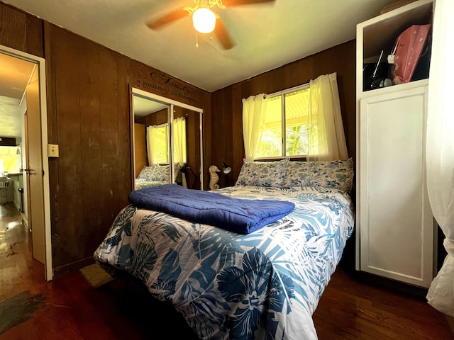 bedroom with dark hardwood / wood-style flooring, wooden walls, a closet, and ceiling fan