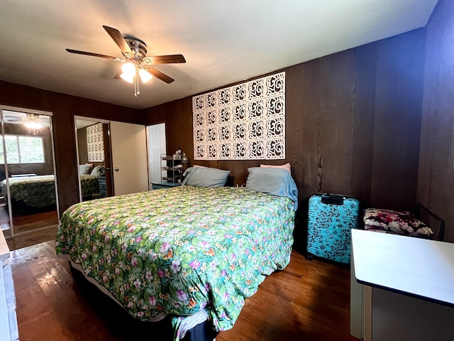 bedroom with hardwood / wood-style flooring, ceiling fan, and two closets