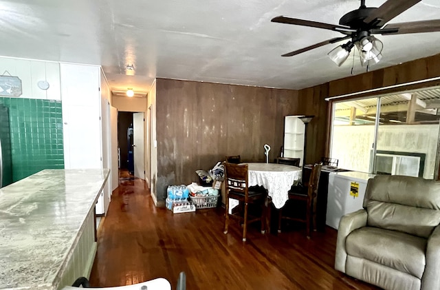 dining area featuring dark wood-type flooring, ceiling fan, and wooden walls