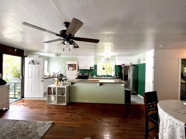 kitchen featuring dark wood-type flooring, a center island, a textured ceiling, white cabinets, and stainless steel fridge with ice dispenser