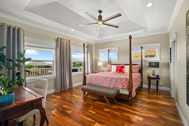 bedroom with ornamental molding, dark hardwood / wood-style floors, ceiling fan, and a tray ceiling