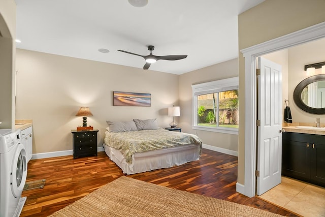 bedroom with independent washer and dryer, sink, ensuite bath, ceiling fan, and light hardwood / wood-style floors