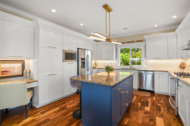 kitchen featuring sink, stainless steel appliances, built in desk, white cabinets, and a kitchen island