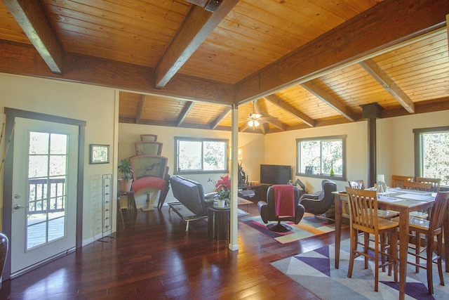 dining space with lofted ceiling with beams, plenty of natural light, and a wood stove