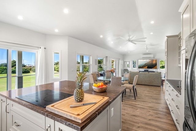 kitchen featuring white cabinetry, a center island, black electric stovetop, light hardwood / wood-style floors, and a wall unit AC