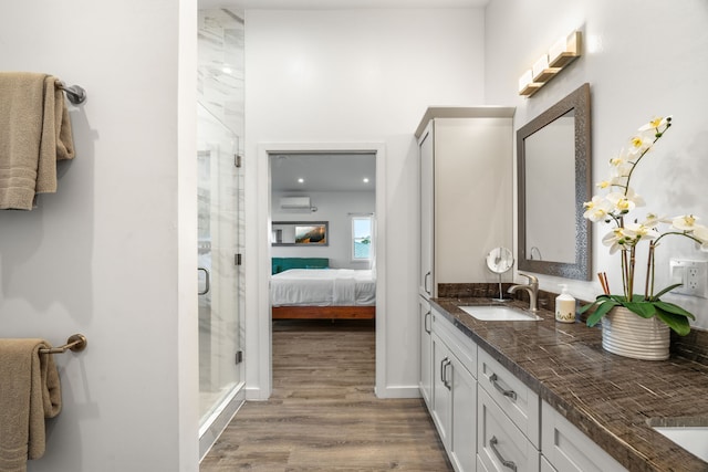 bathroom featuring vanity, hardwood / wood-style floors, a wall mounted AC, and a shower with shower door