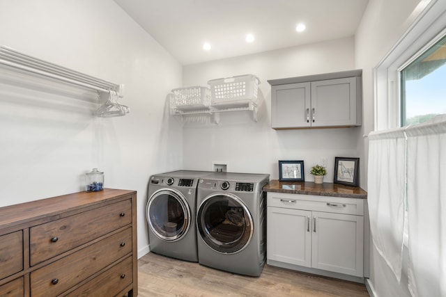 laundry room featuring cabinets, washing machine and clothes dryer, and light wood-type flooring