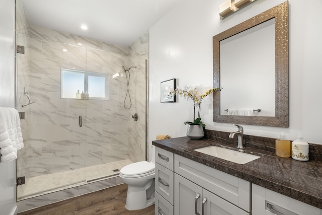 bathroom featuring vanity, toilet, a shower with shower door, and hardwood / wood-style floors