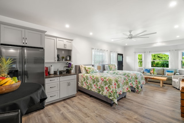 bedroom featuring ceiling fan, stainless steel fridge, sink, and light wood-type flooring