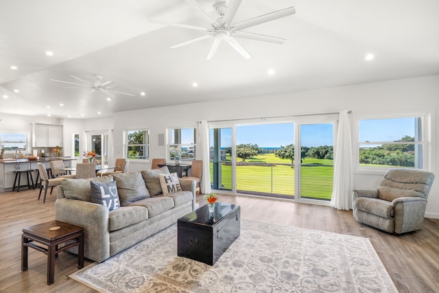 living room with ceiling fan, vaulted ceiling, a healthy amount of sunlight, and light wood-type flooring