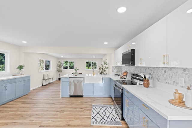 kitchen featuring sink, light wood-type flooring, kitchen peninsula, stainless steel appliances, and decorative backsplash