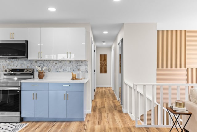 kitchen featuring white cabinetry, decorative backsplash, stainless steel appliances, and light wood-type flooring