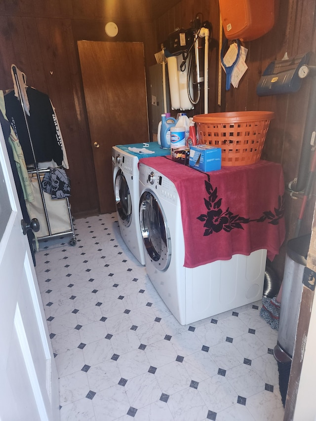 laundry room featuring wooden walls and washer and dryer