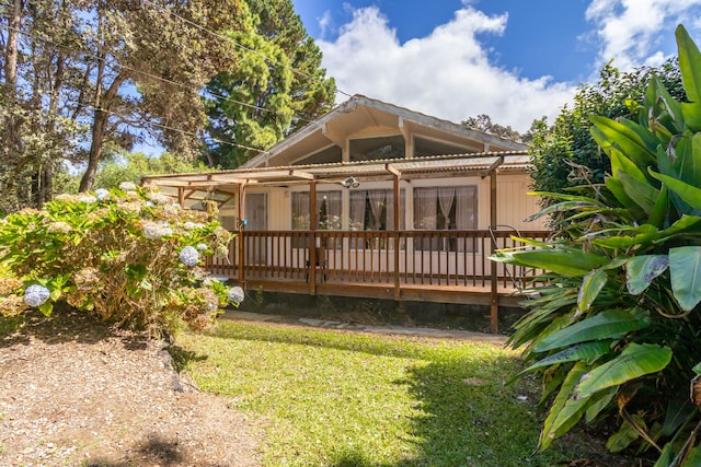 rear view of property with a deck and a lawn