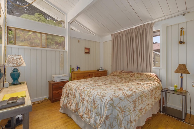 bedroom with lofted ceiling with beams, wooden walls, wooden ceiling, and light hardwood / wood-style floors