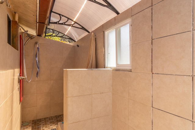 bathroom with tiled shower and vaulted ceiling