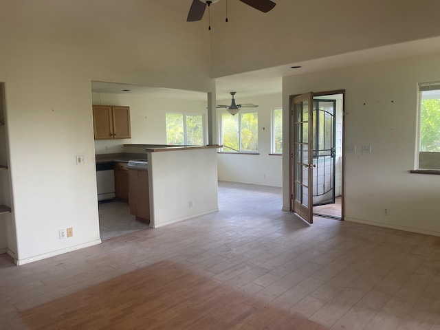 unfurnished living room with ceiling fan, light hardwood / wood-style flooring, and a high ceiling