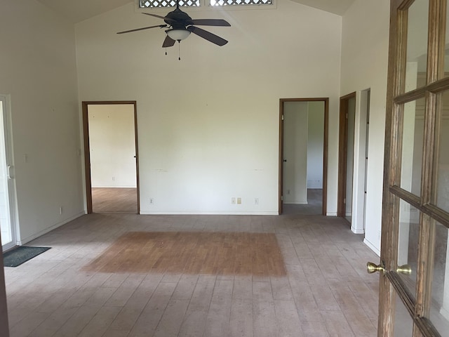 empty room featuring a high ceiling, ceiling fan, and light wood-type flooring