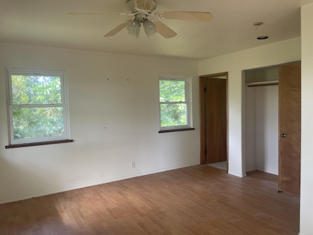 unfurnished bedroom featuring multiple closets, ceiling fan, and hardwood / wood-style flooring