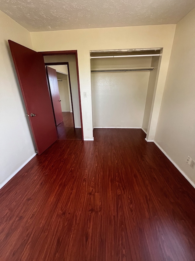 unfurnished bedroom featuring a closet, dark hardwood / wood-style floors, and a textured ceiling