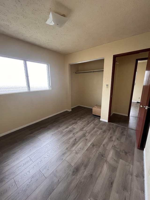 unfurnished bedroom with hardwood / wood-style flooring, a closet, and a textured ceiling