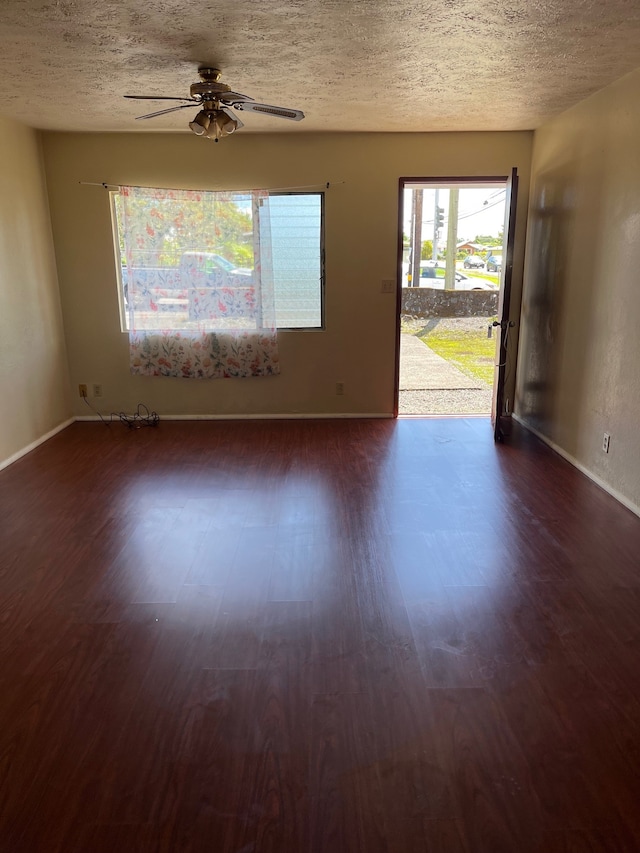 empty room featuring dark wood-type flooring, ceiling fan, and a textured ceiling