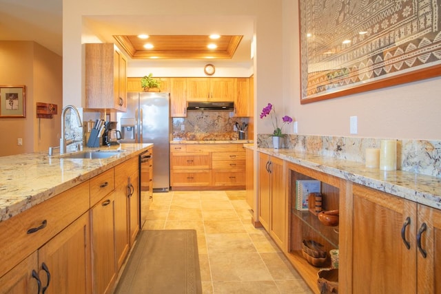 kitchen featuring a raised ceiling, sink, backsplash, light stone counters, and stainless steel appliances