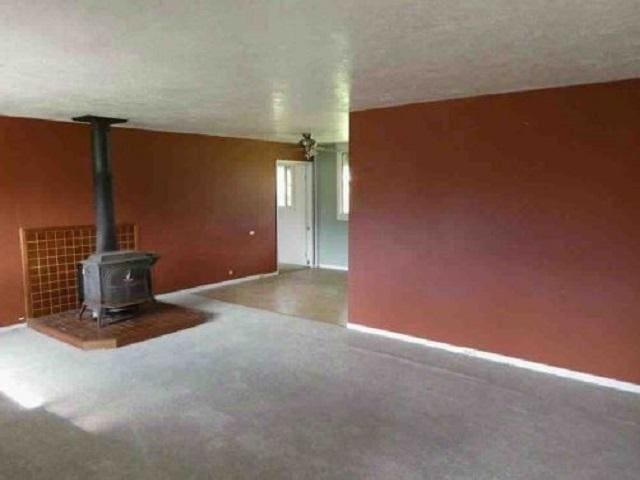 unfurnished living room with a wood stove and carpet flooring