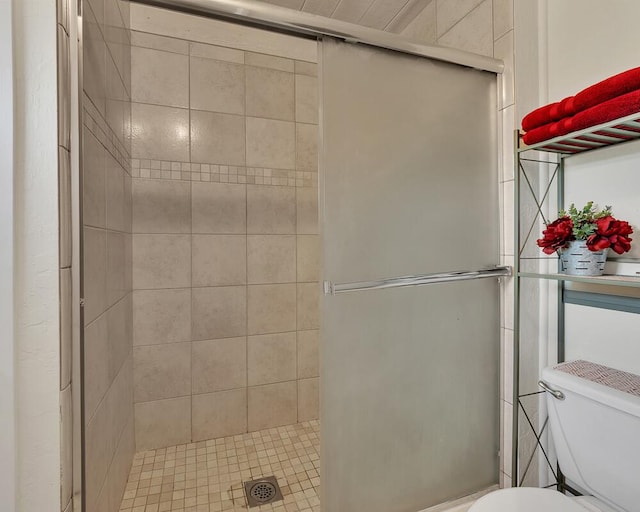 bathroom featuring toilet and a shower with shower door