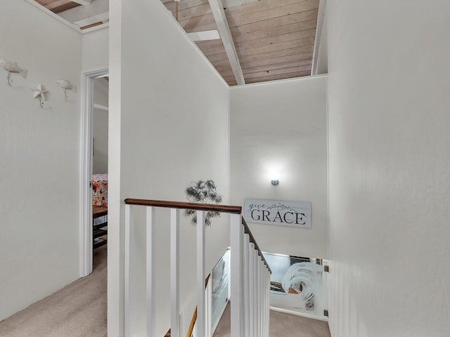 stairway with beam ceiling, wood ceiling, and carpet floors