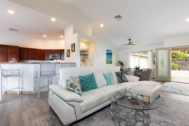 living room with vaulted ceiling, light wood-style flooring, visible vents, and recessed lighting