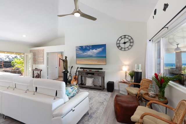 living area featuring high vaulted ceiling, light wood finished floors, and a ceiling fan