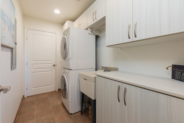 washroom with stacked washer and clothes dryer, cabinet space, and recessed lighting