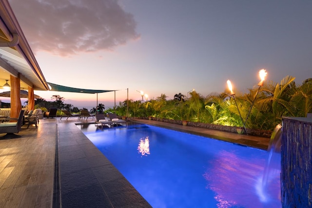 pool at dusk with a patio area and an outdoor pool