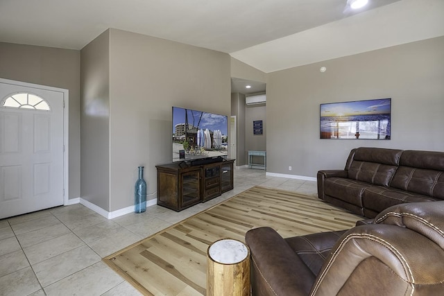 living room featuring light tile patterned floors, vaulted ceiling, and a wall unit AC