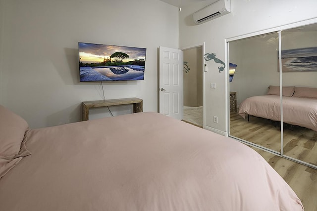 bedroom with hardwood / wood-style flooring, a wall mounted AC, and a closet