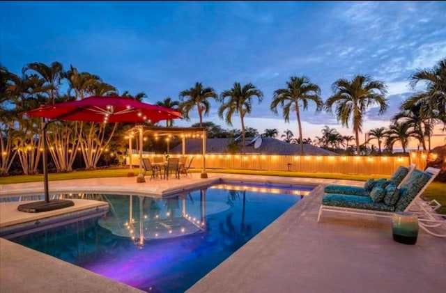 pool at dusk with a patio area