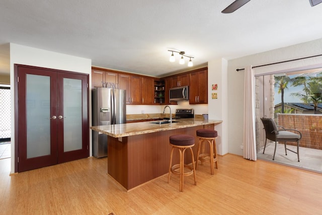 kitchen featuring french doors, appliances with stainless steel finishes, sink, and light hardwood / wood-style flooring