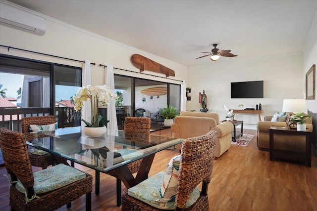 dining room with a wall mounted AC, wood finished floors, and a healthy amount of sunlight