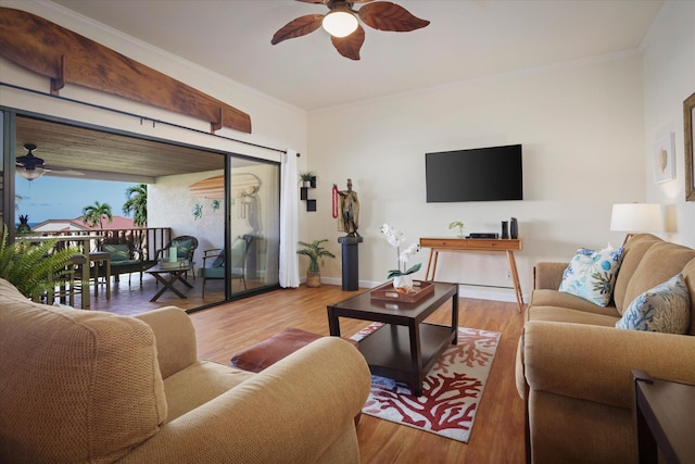 living area featuring a ceiling fan, baseboards, ornamental molding, and wood finished floors