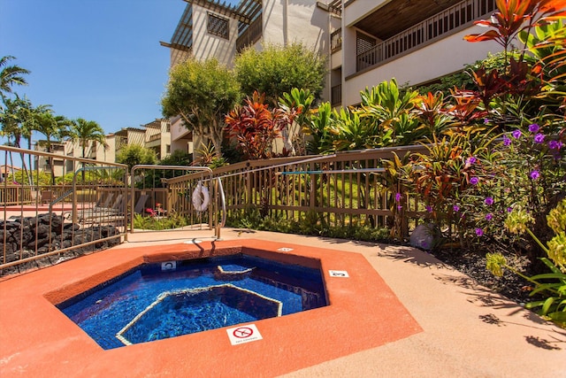 view of pool with fence and a hot tub