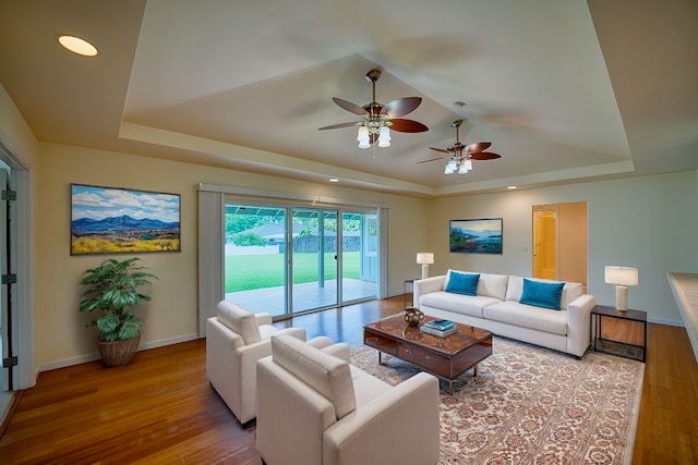 living room with a raised ceiling and light hardwood / wood-style floors