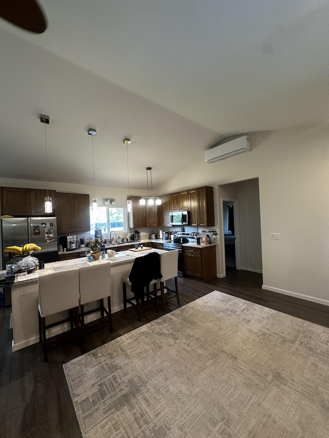 kitchen with vaulted ceiling, appliances with stainless steel finishes, a wall mounted air conditioner, pendant lighting, and a center island