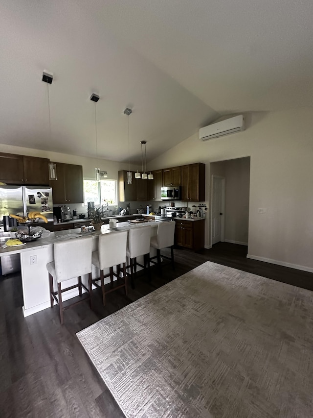 kitchen with lofted ceiling, a breakfast bar area, appliances with stainless steel finishes, hanging light fixtures, and an AC wall unit