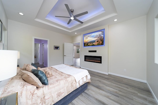 bedroom featuring ceiling fan, hardwood / wood-style floors, and a tray ceiling